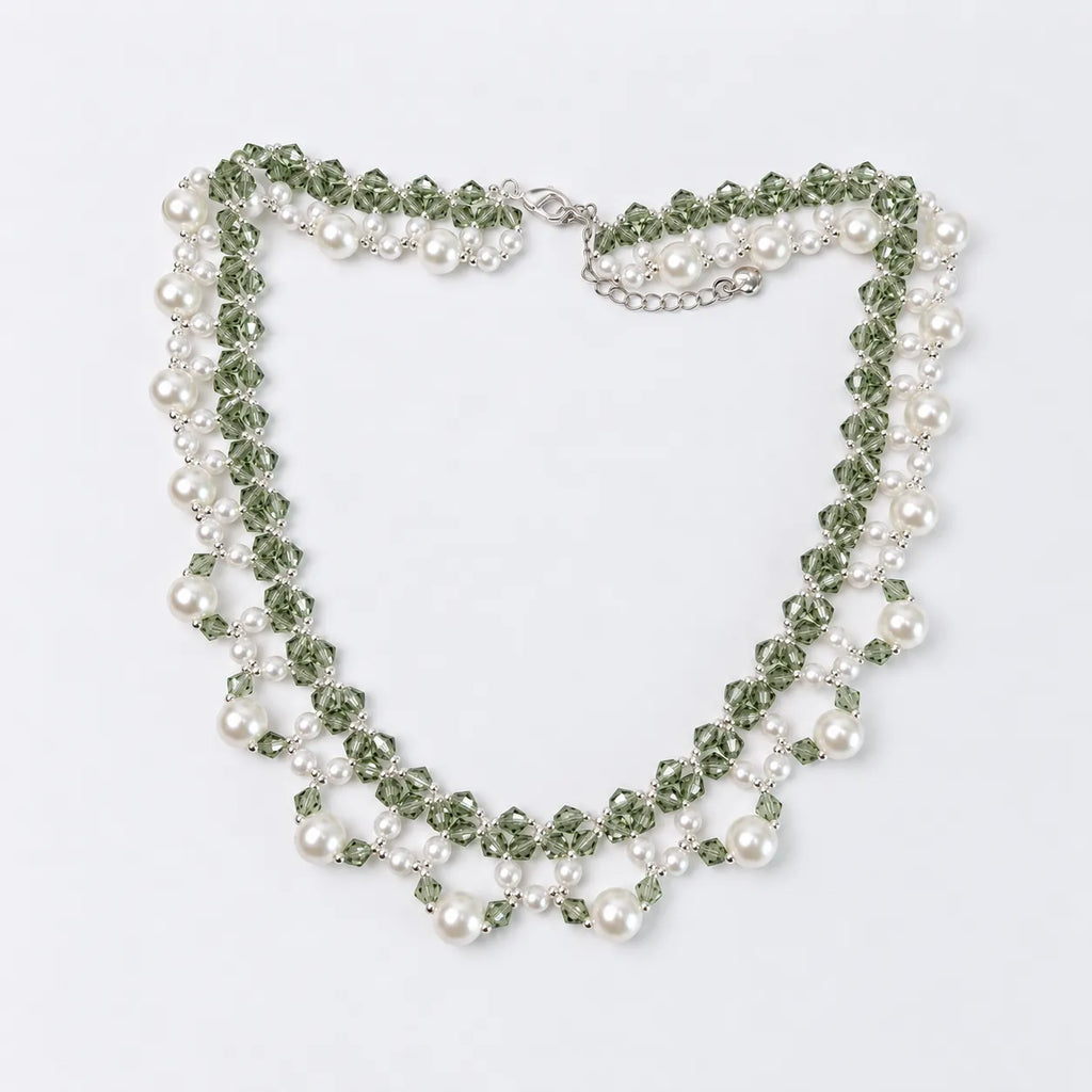 A multi-strand beaded necklace featuring green faceted beads, white faux pearls, and silver-toned metal links, displayed on a clean white background.