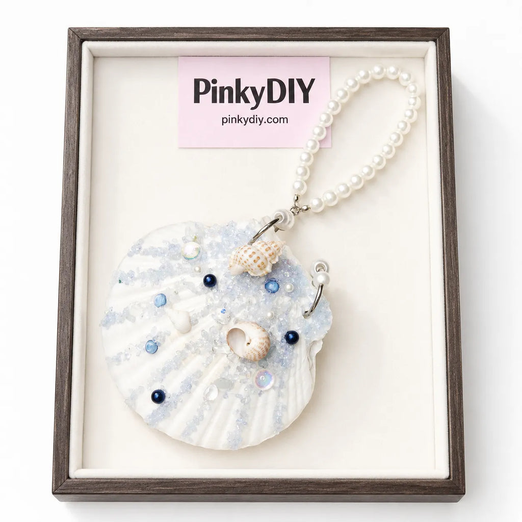 Necklace with shell pendant and pearls in a wooden frame, branded 'PinkyDIY'.